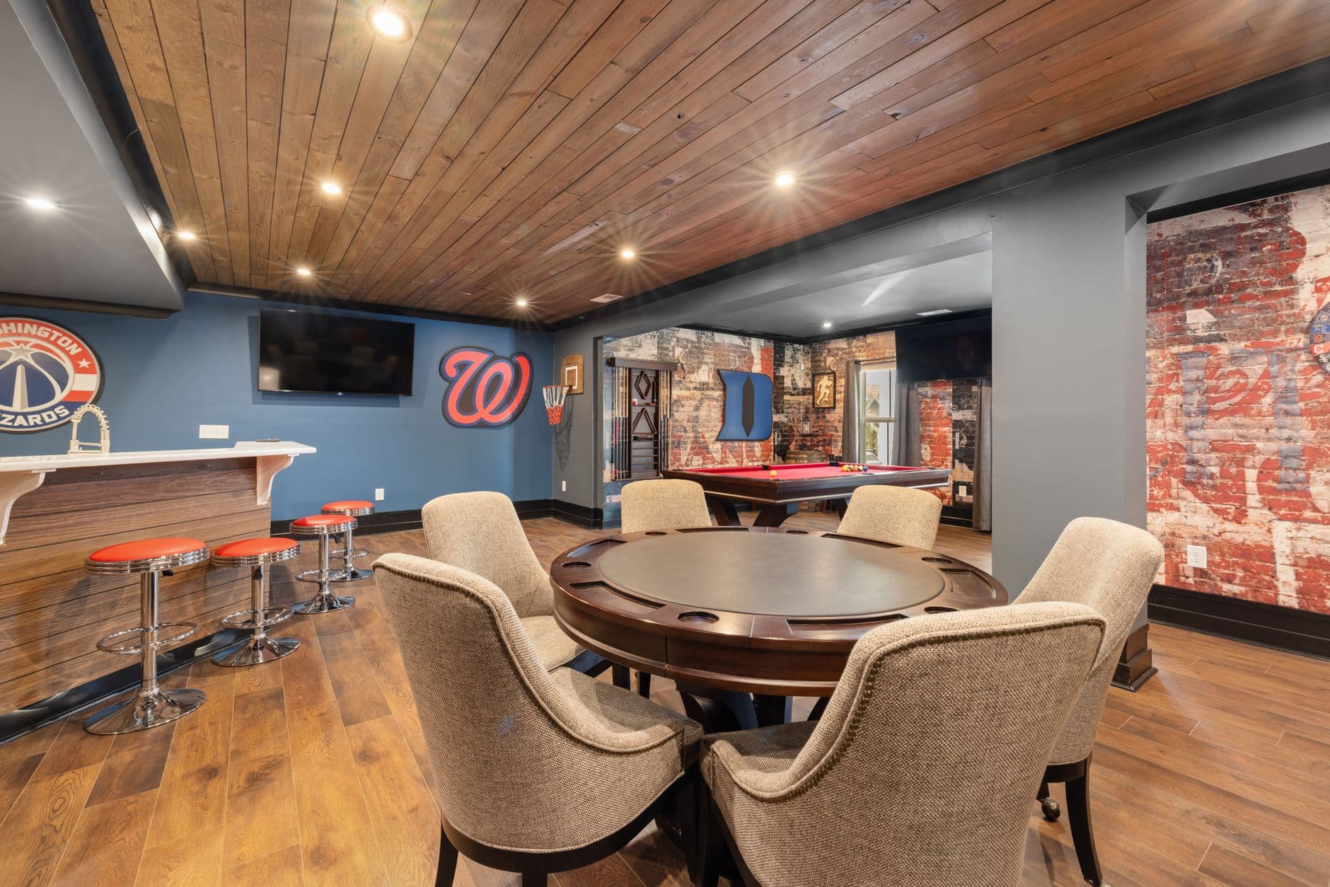 A basement home bar and game room with seating and a pool table
