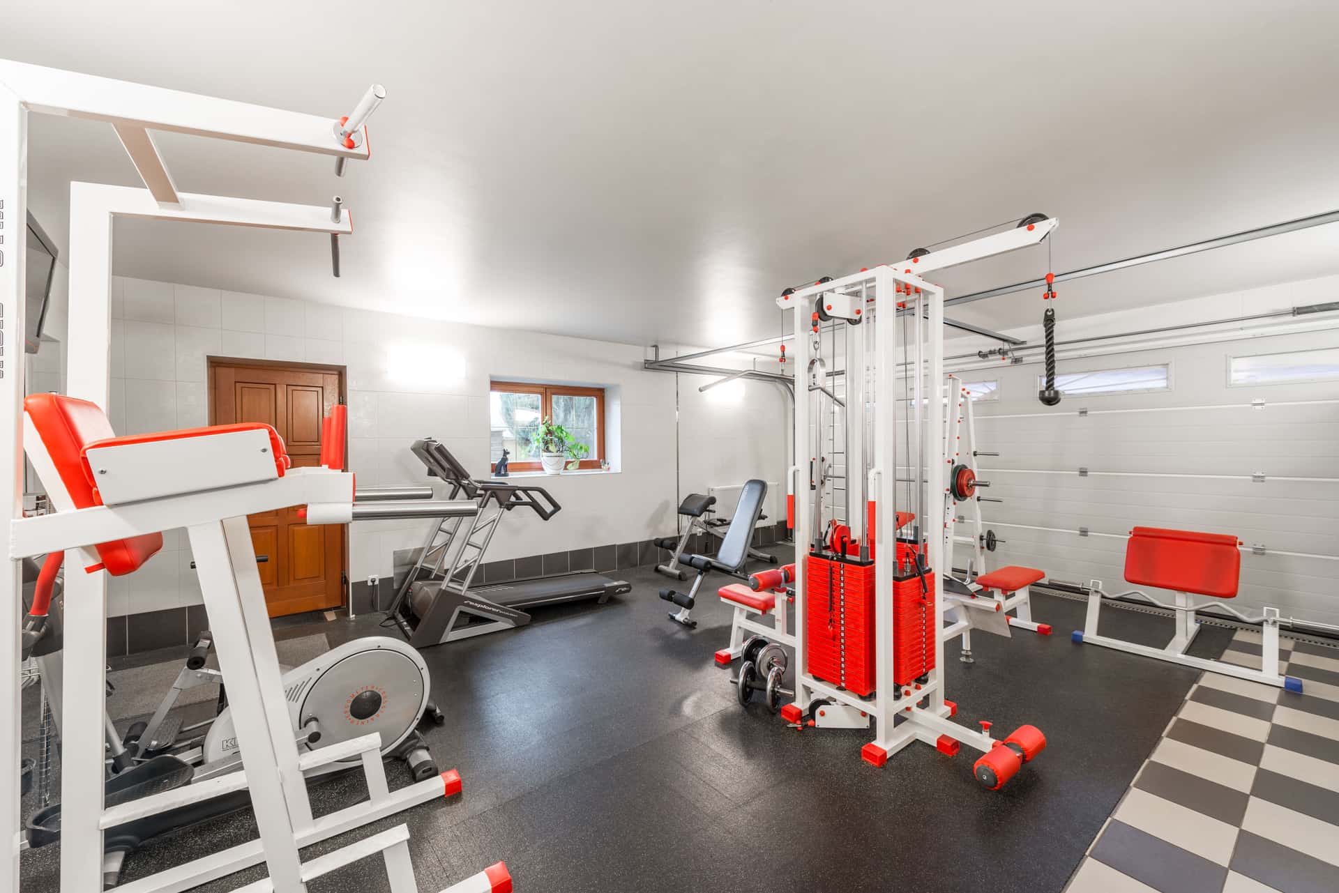 A complete budget home gym built in a garage — rack, barbell, bench and flooring