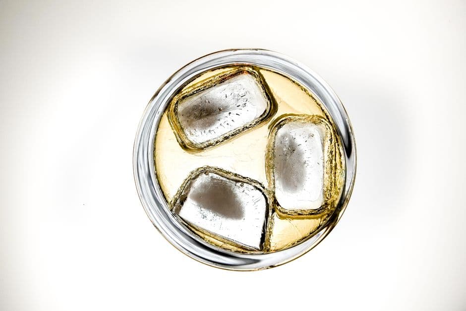 A chilled drink over ice cubes in a clear glass, seen from above
